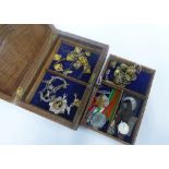 Carved wooden box containing a collection of WWII medals, various military cap badges and buttons,