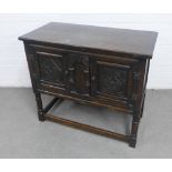 Dark oak cabinet, with a pair of carved cupboard doors opening to reveal a shelved interior, on