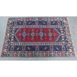 Persian rug, red field with hooked border enclosing five diamond lozenges with spiders within,