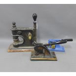 Two Victorian punch / presses on a wooden base and another later design, (3)
