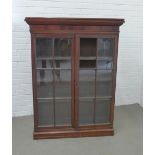Mahogany cabinet with a stepped cornice over a pair of glazed doors with shelved interior, likely