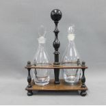 Victorian rosewood and ebonised decanter stand containing a pair of glass decanters with tear drop