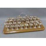 Collection of Epns shot cups on a wooden tray style base, 33 cups in total with one missing, 52cm