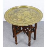 Eastern engraved circular brass topped table on a Benares style folding stand, 65 x 56cm