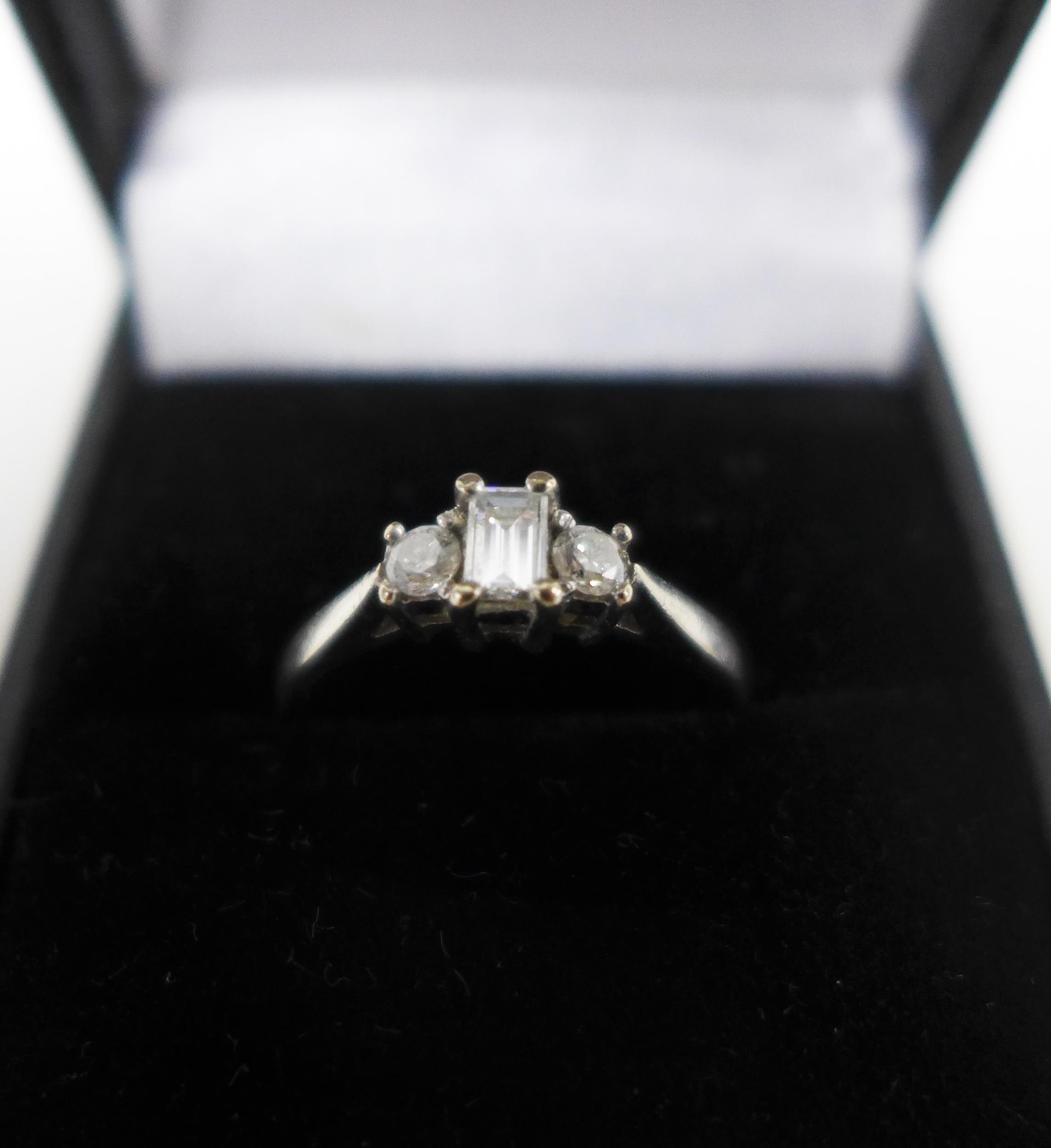 18ct white gold and three stone diamond ring, claw set with a baguette cut diamond flanked by round