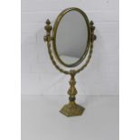 Ornate brass dressing table mirror, the oval plate supported by a clasped hand, 65 x 37cm