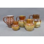 A collection of Doulton and other stoneware jugs and a Torquay pottery jug, (5)