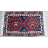 Persian rug, red field with two hooked medallions and flowerhead borders, 125 x 80cm