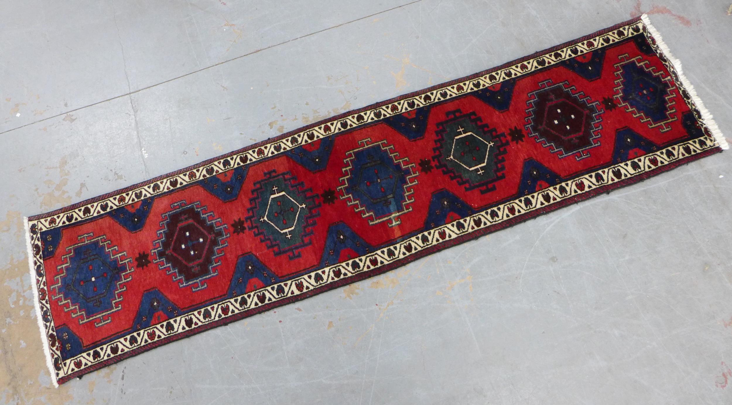 Kazak style runner with red field and seven medallions, 290 x 74cm