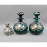 A pair of silver overlaid green glass scent bottles with stoppers and another smaller scent