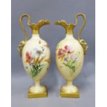 A pair of Royal Worcester ewers, blush ivory ground and with hand painted flowers and gilded satyr