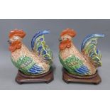 Two Chinese polychrome glazed cockerels, on shaped hardwood stands, (a/f) (2) 20cm