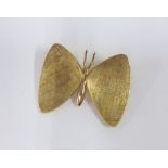 An unmarked yellow metal butterfly brooch with textured wings, 3.5cm wide