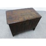An antique dark oak box, the carved front with arched panels containing leaf design, with an iron