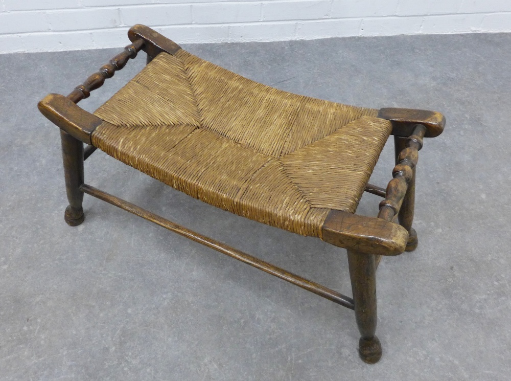 An Arts & Crafts elm stool with a concave woven rush seat, 39 x 76 x 33cm.