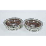 A matched set of two early 19th century silver wine bottle coasters, crested with turned wooden