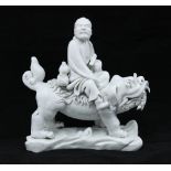 Chinese blanc de chine figure group of an immortal figure riding a temple lion, impressed seal mark,