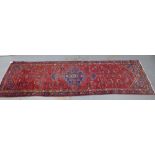 North West Persian runner, red field with a pole medallion and flowerhead borders, 306 x 87cm