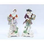 A pair of Continental porcelain male and female figures, both carrying a basket of flowers, the