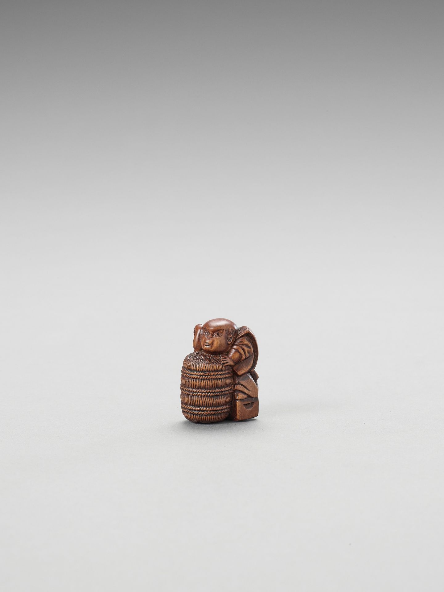 A WOOD NETSUKE OF FUKUSUKE WITH RICE BAIL