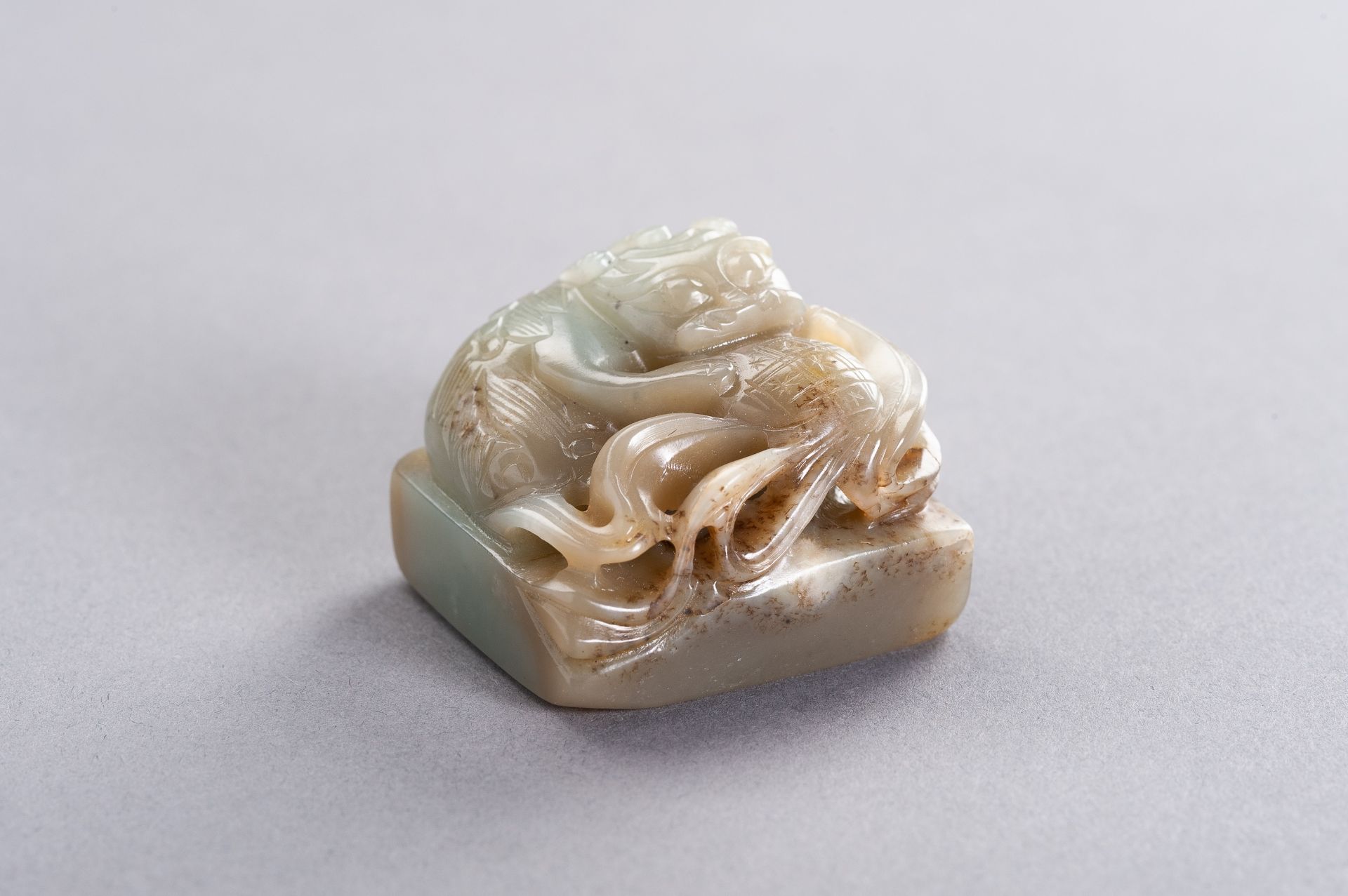A CELADON AND RUSSET JADE 'QILIN' SEAL, LATE QING TO REPUBLIC