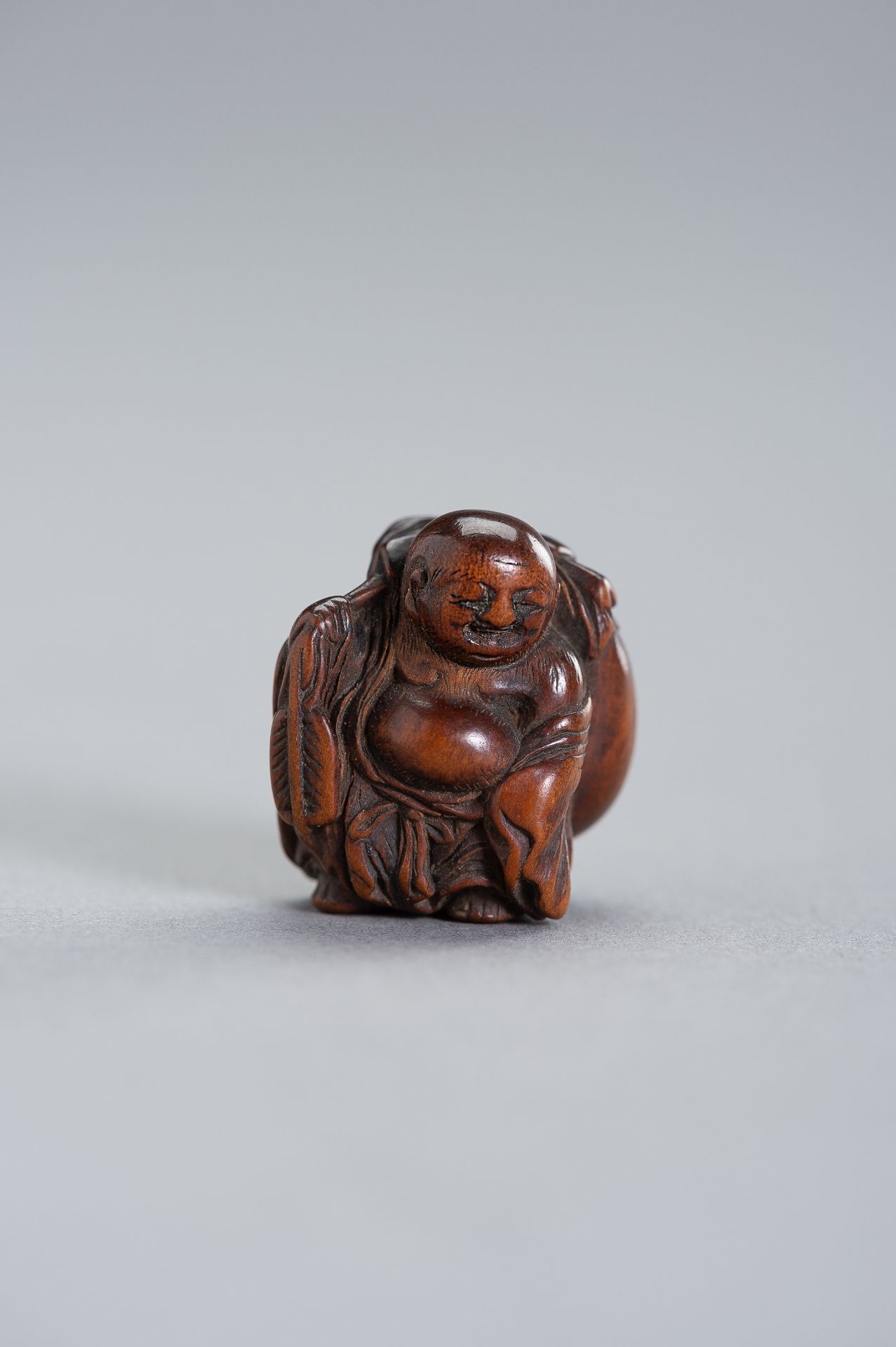 A RARE MINIATURE WOOD NETSUKE OF HOTEI