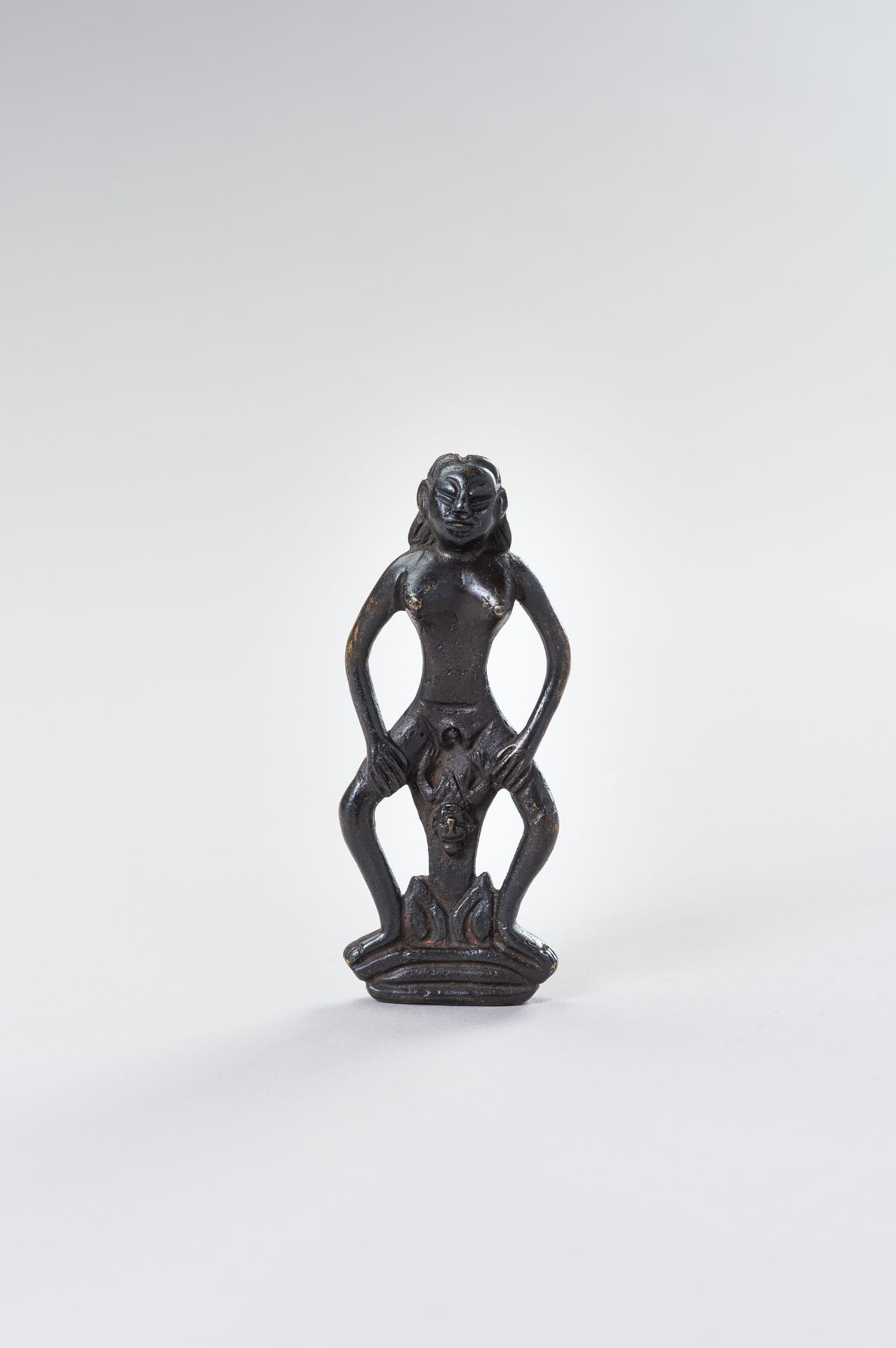 A TRIBAL BRONZE FIGURE OF A WOMAN GIVING BIRTH