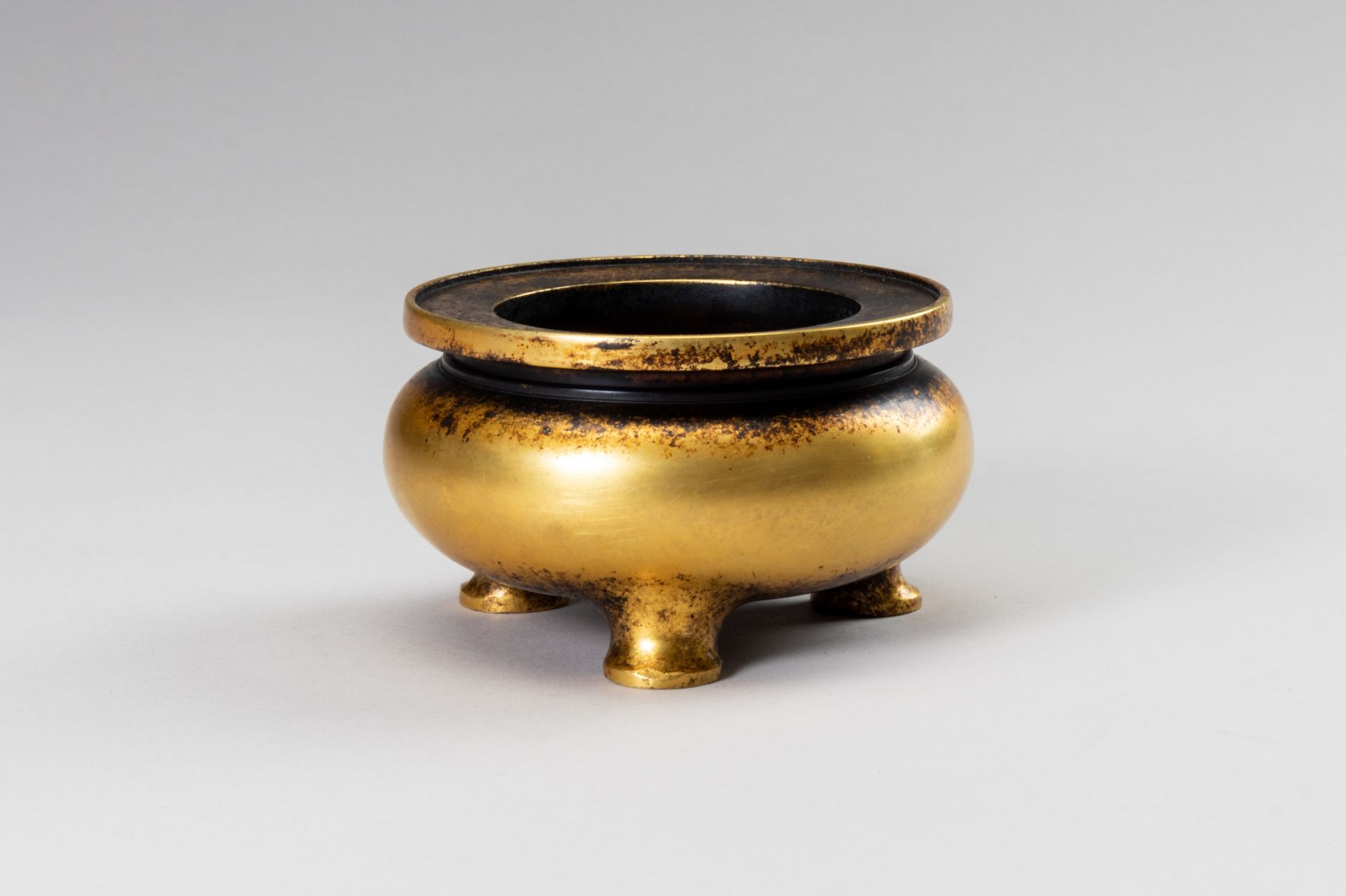 A SMALL GILT-BRONZE TRIPOD CENSER