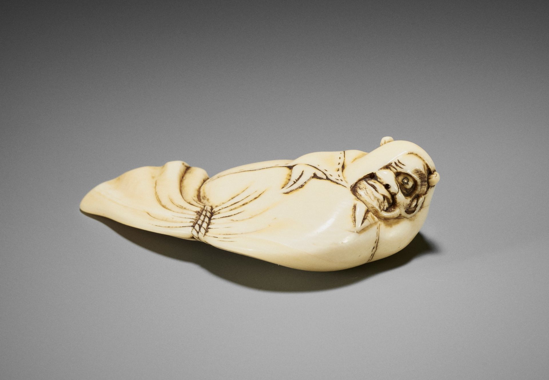 AN IVORY NETSUKE OF ONI IN SHOKI'S BAG