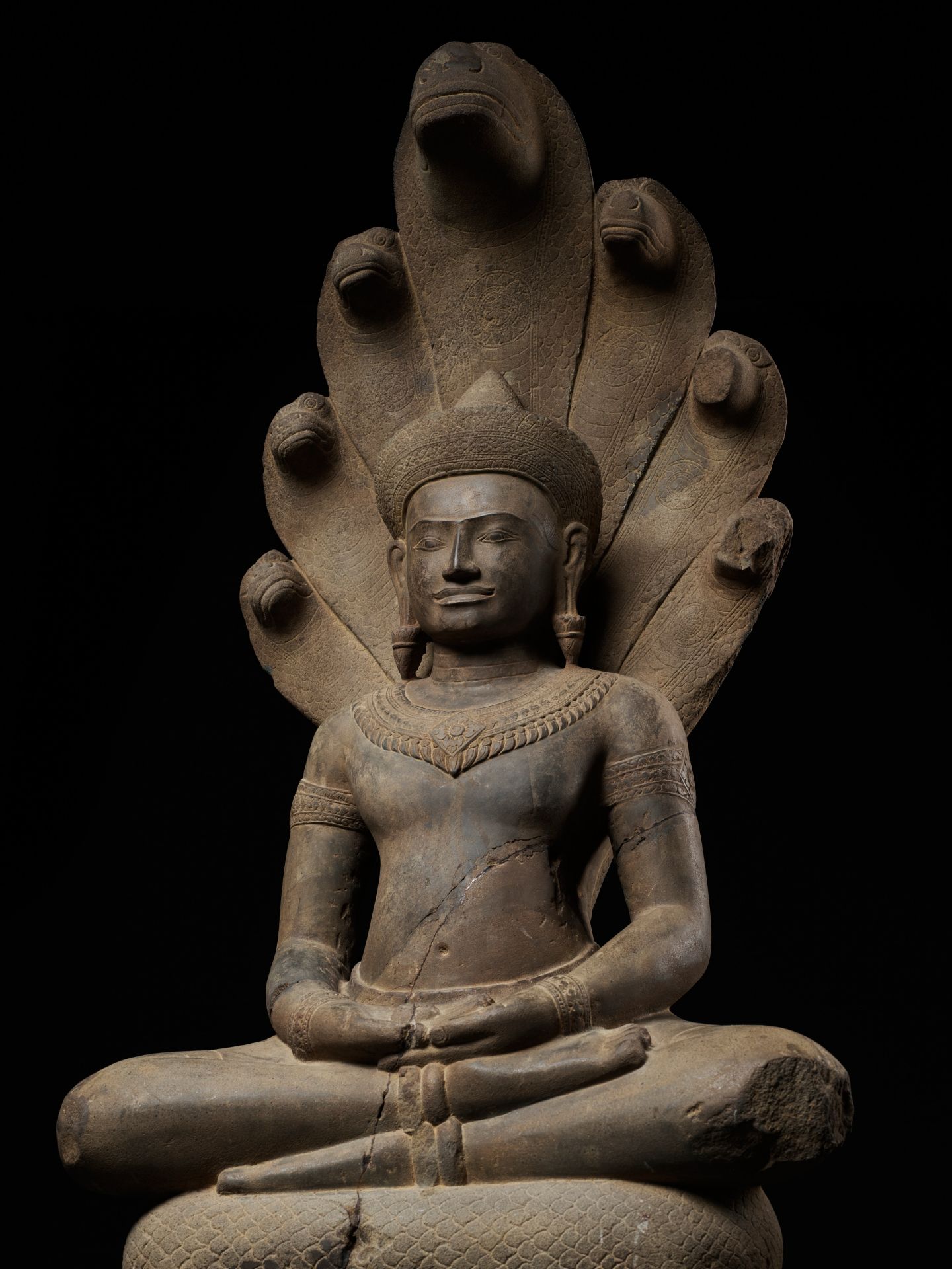 A MONUMENTAL SANDSTONE FIGURE OF BUDDHA MUCHALINDA, ANGKOR PERIOD