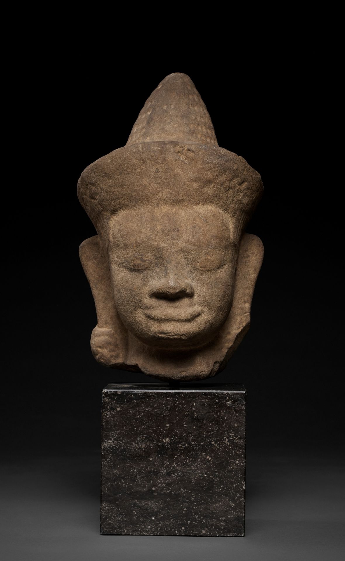 A MONUMENTAL SANDSTONE HEAD OF A MALE DEITY, ANGKOR WAT STYLE