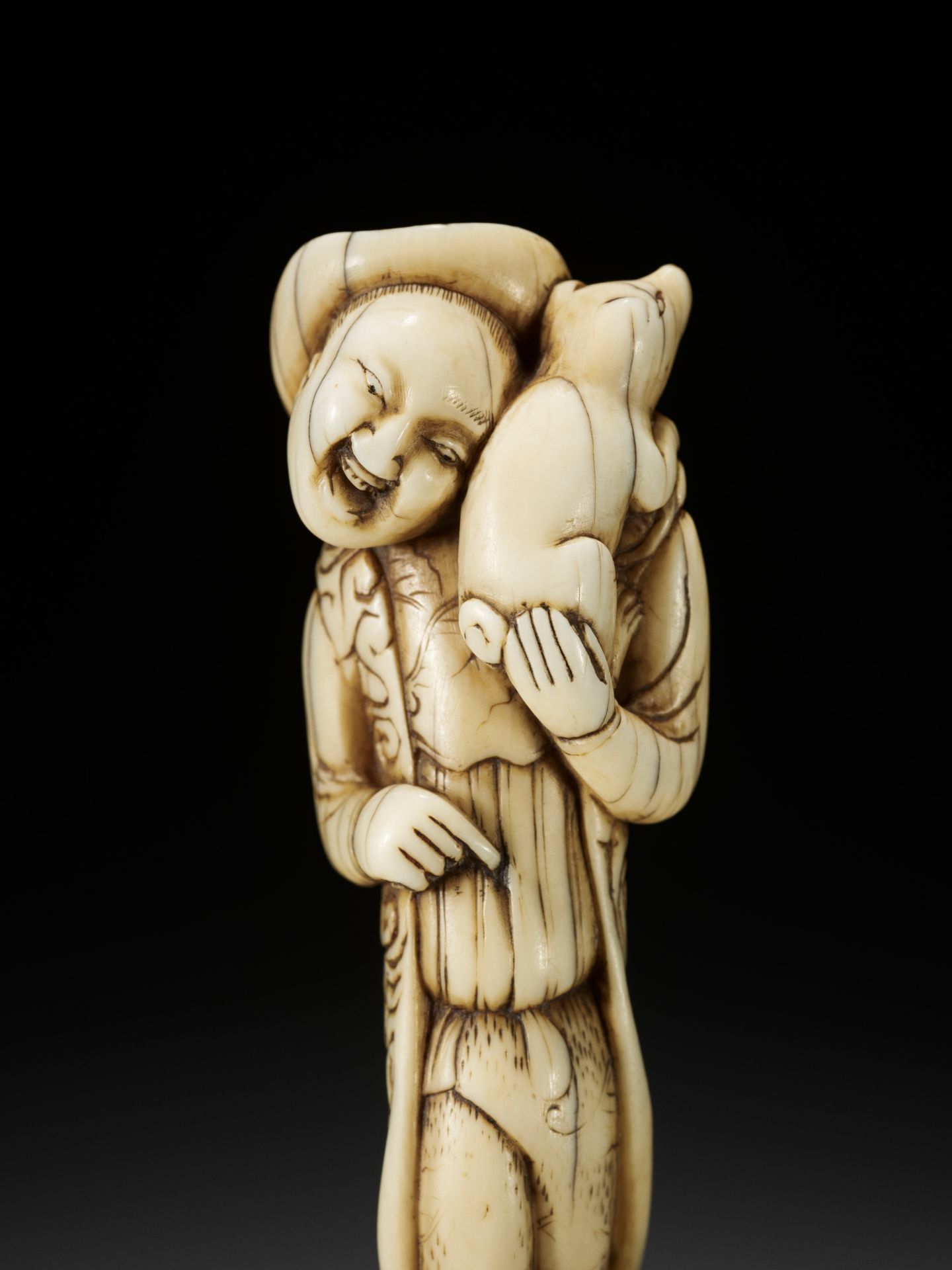 A GOOD IVORY NETSUKE OF A DUTCHMAN WITH DOG