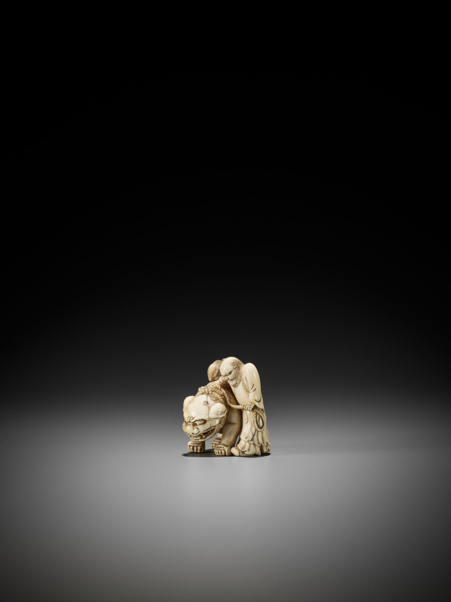 AN IVORY NETSUKE OF A FOREIGNER FROM SENHA LEADING A SHISHI - Bild 2 aus 12