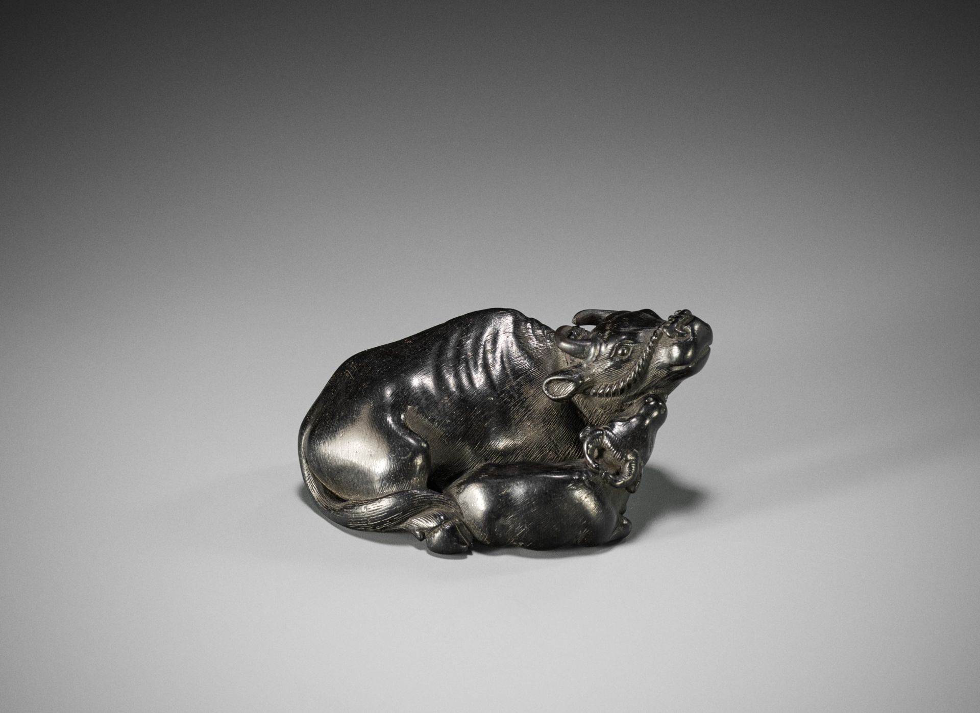 A SUPERB KYOTO SCHOOL EBONY WOOD NETSUKE OF A RECUMBENT COW WITH CALF