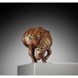 A GOOD WOOD NETSUKE OF A GRAZING HORSE