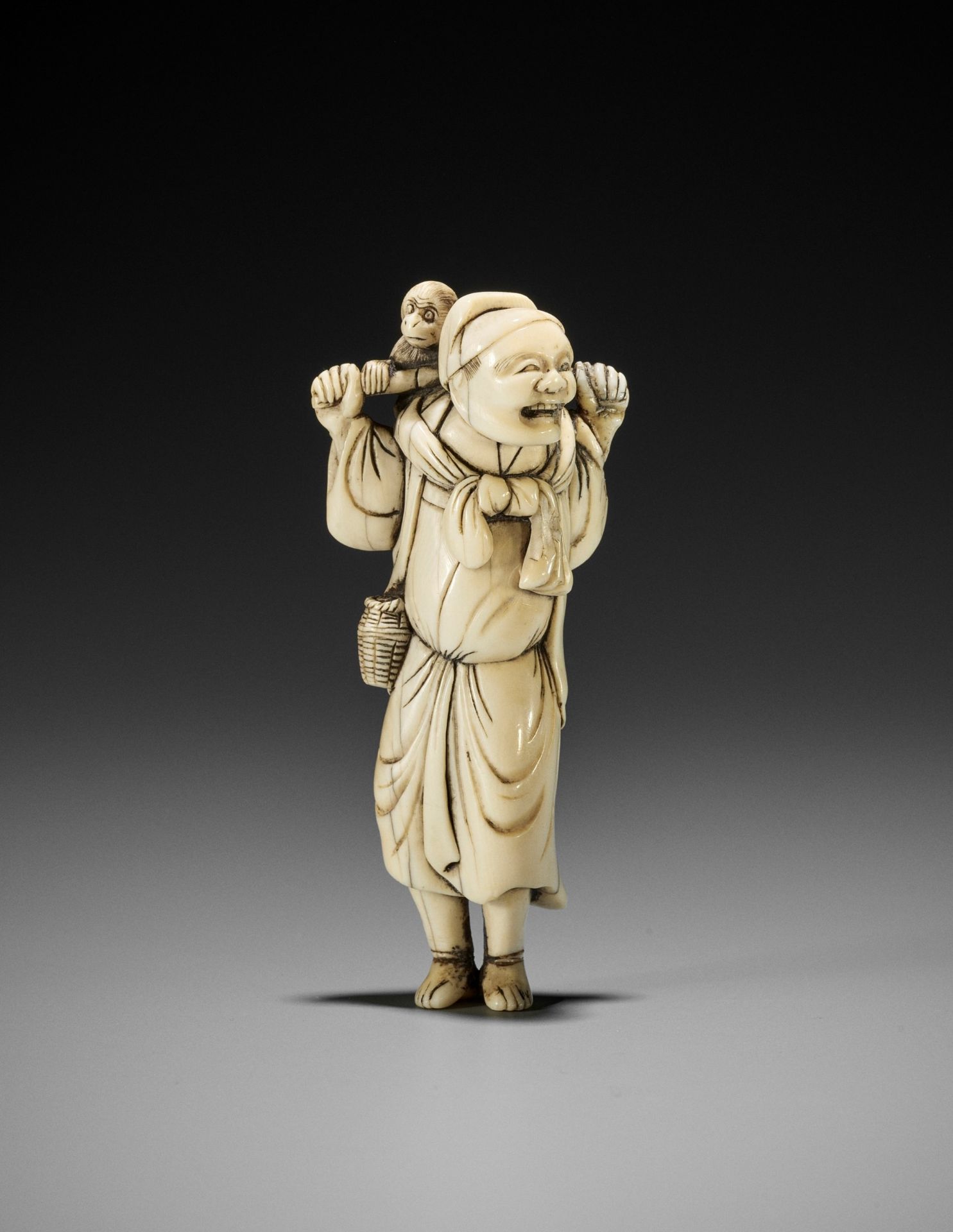 AN IVORY NETSUKE OF A SARUMAWASHI WITH MONKEY