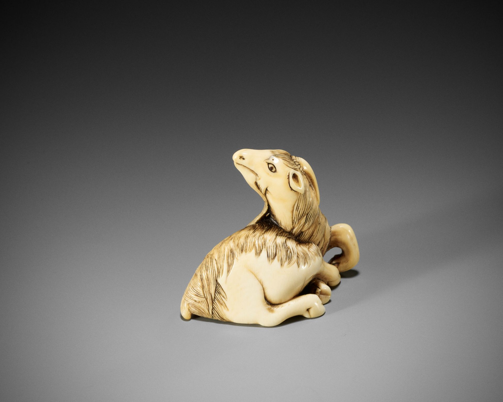 A VERY RARE IVORY NETSUKE OF A KIRIN GOAT, ATTRIBUTED TO MITSUHARU