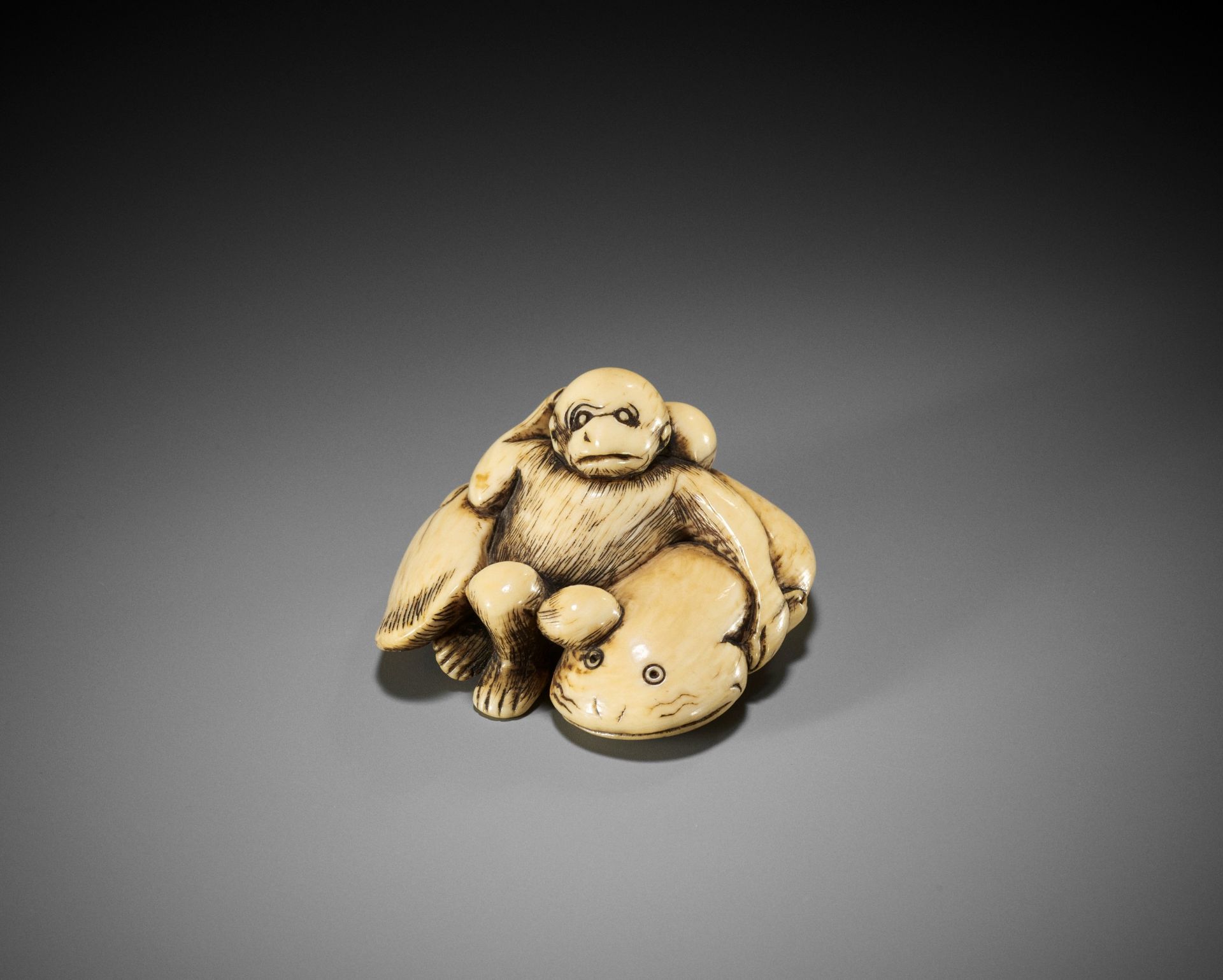 AN IVORY NETSUKE OF A MONKEY AND GIANT NAMAZU (EARTHQUAKE FISH)