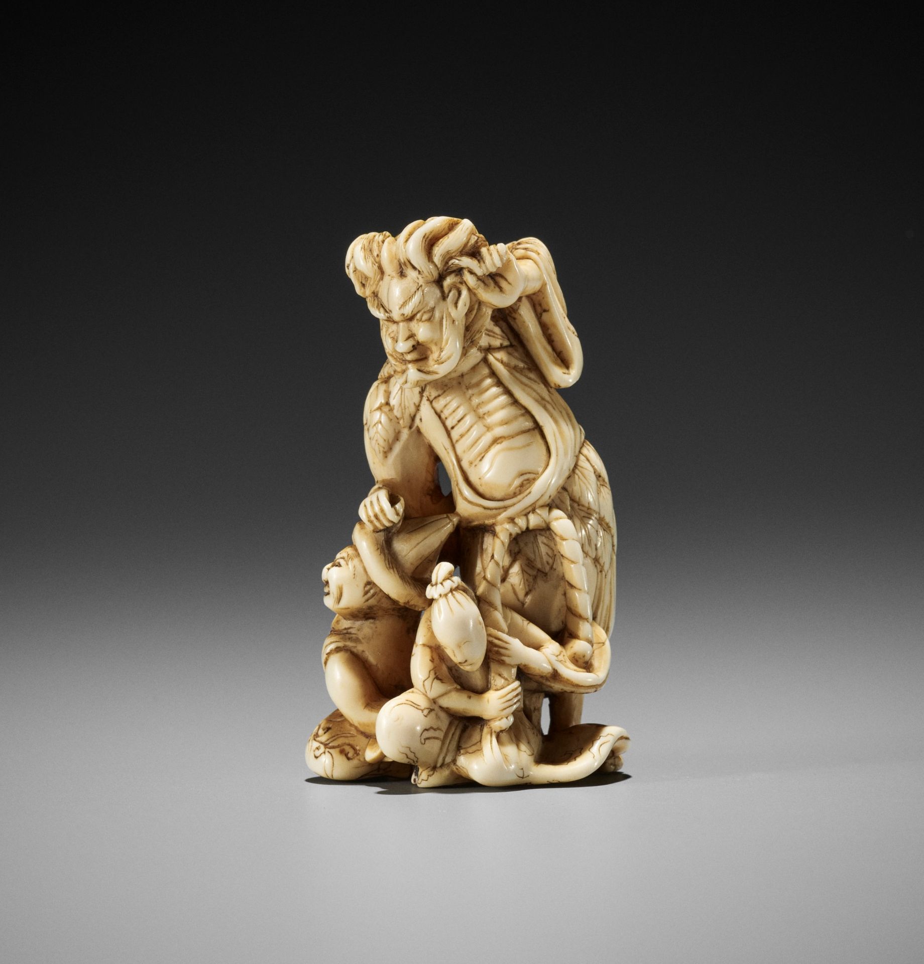 A RARE AND UNUSUAL IVORY NETSUKE OF A SENNIN AND TWO ATTENDANTS