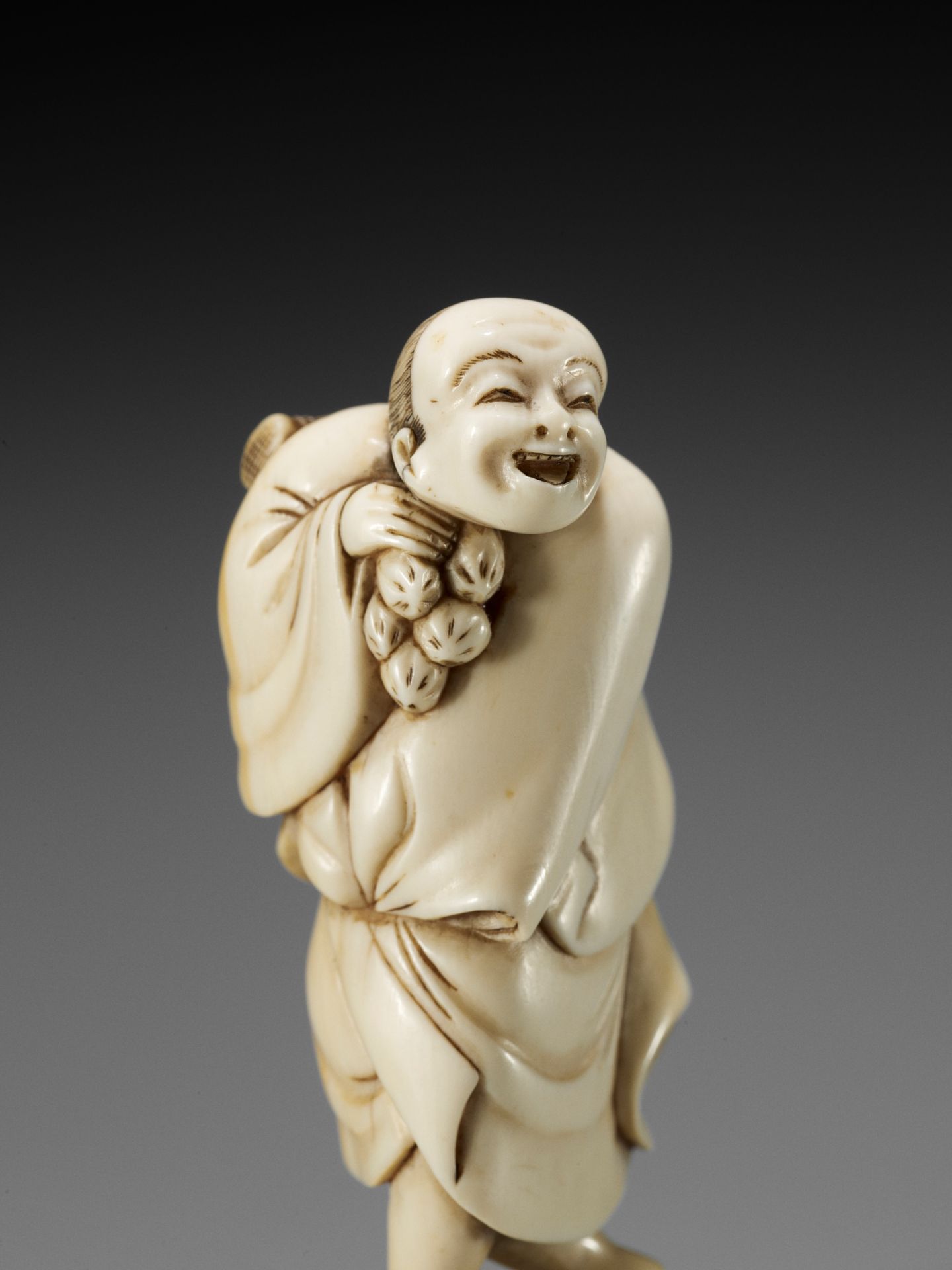 A GOOD IVORY NETSUKE OF A STREET VENDOR