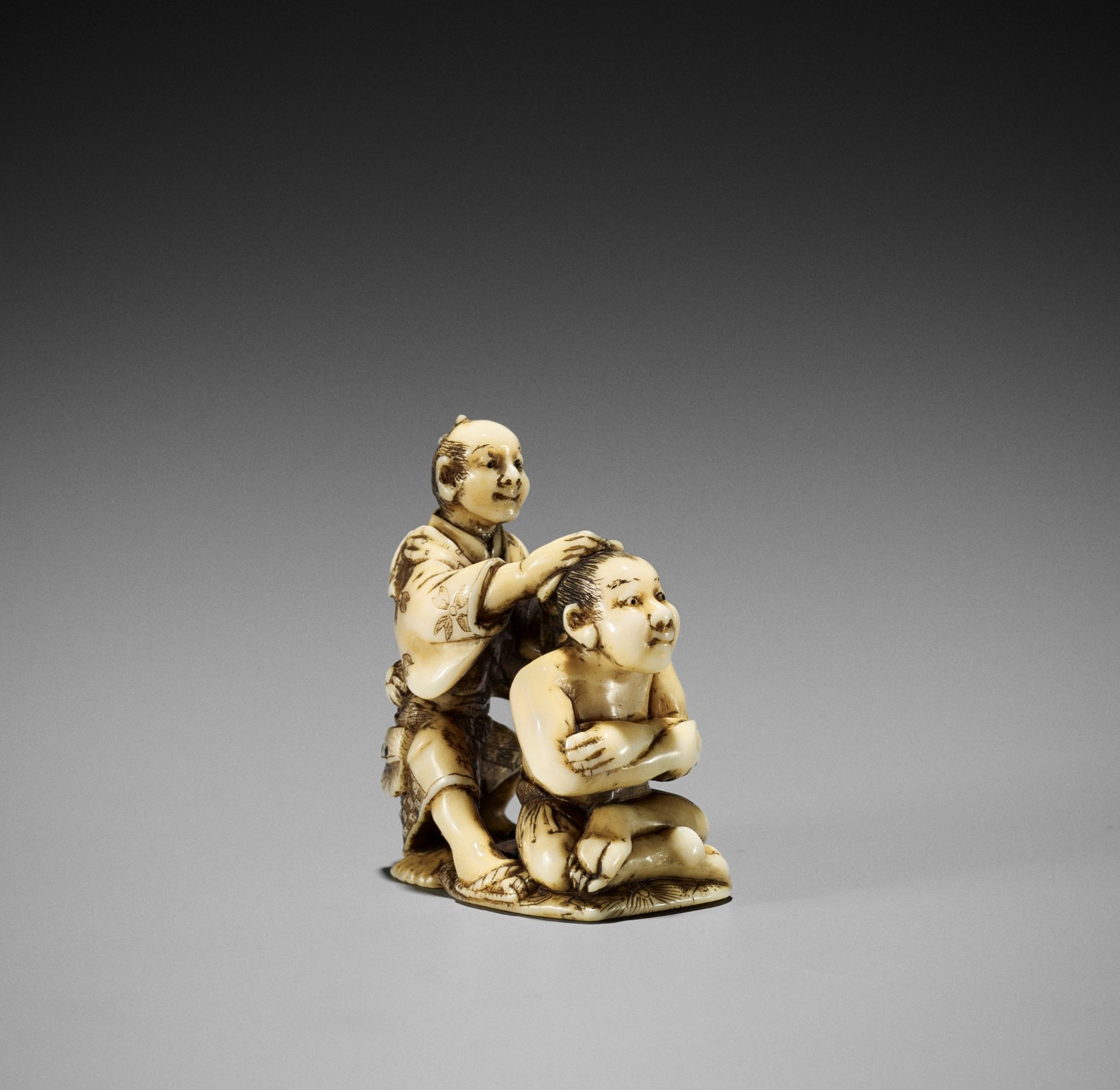 GYOKUSAI: A RARE IVORY NETSUKE OF A SUMO WRESTLER AND HAIRDRESSER