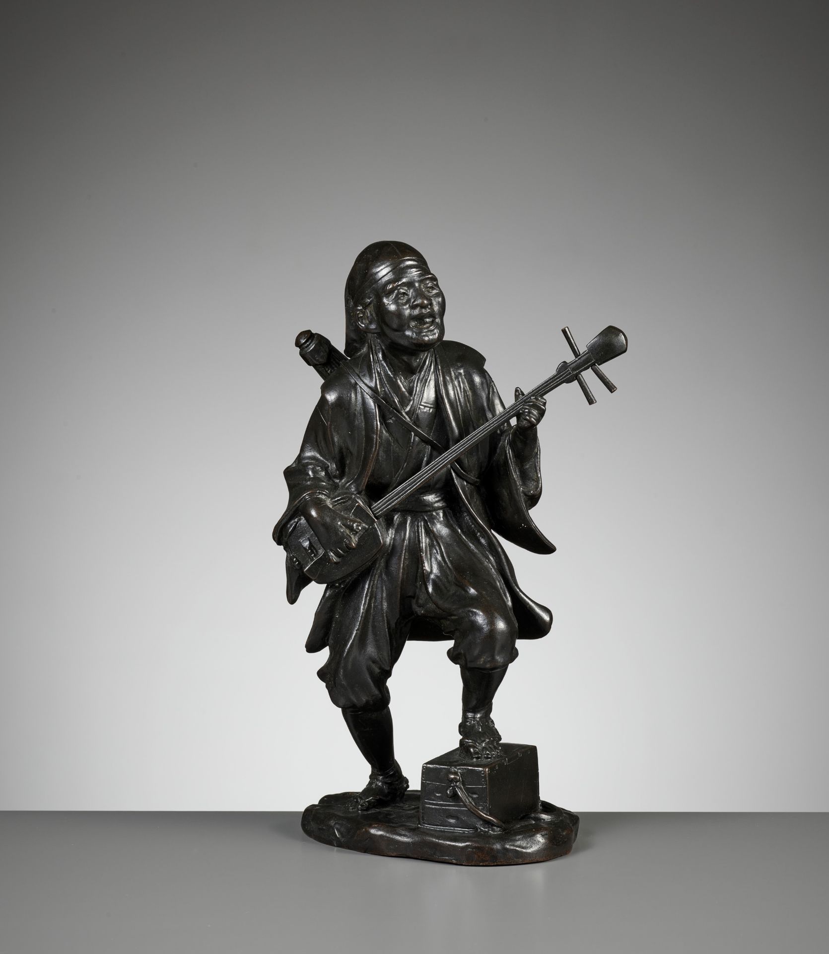 SEIYA: A BRONZE FIGURE OF A MUSICIAN PLAYING A SHAMISEN