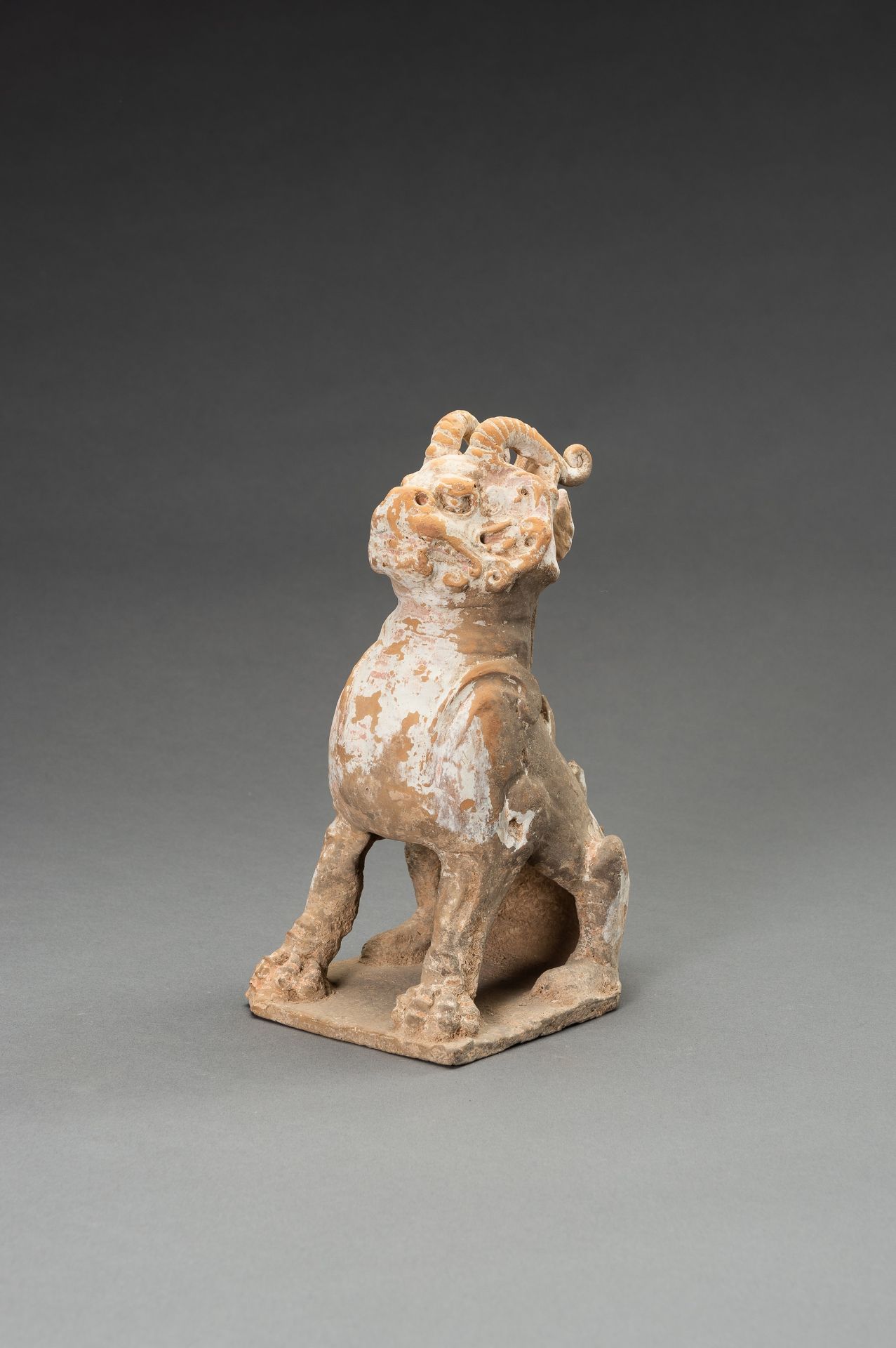 A POTTERY FIGURE OF A HORNED GUARDIAN BEAST, TANG DYNASTY OR EARLIER