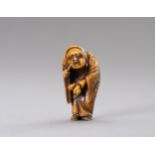 A STAINED IVORY NETSUKE OF DARUMA