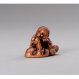 A BOXWOOD NETSUKE OF OKAME CARESSING A TENGU MASK