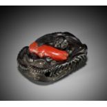 A RARE EBONY AND CORAL NETSUKE OF AN ISLANDER IN WAVES