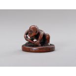 HOKEI: A BOXWOOD NETSUKE OF A MAN FIXING A WHEEL