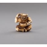 AN IVORY NETSUKE OF AN ONI COMBING HIS HAIR