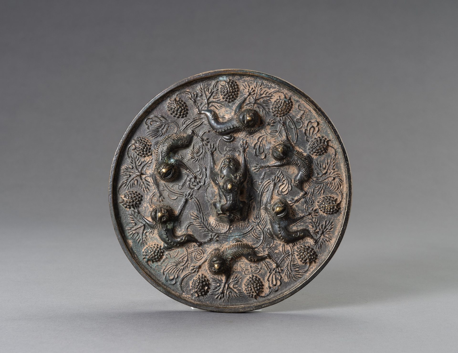 A TANG-STYLE BRONZE 'LIONS AND GRAPEVINES' MIRROR