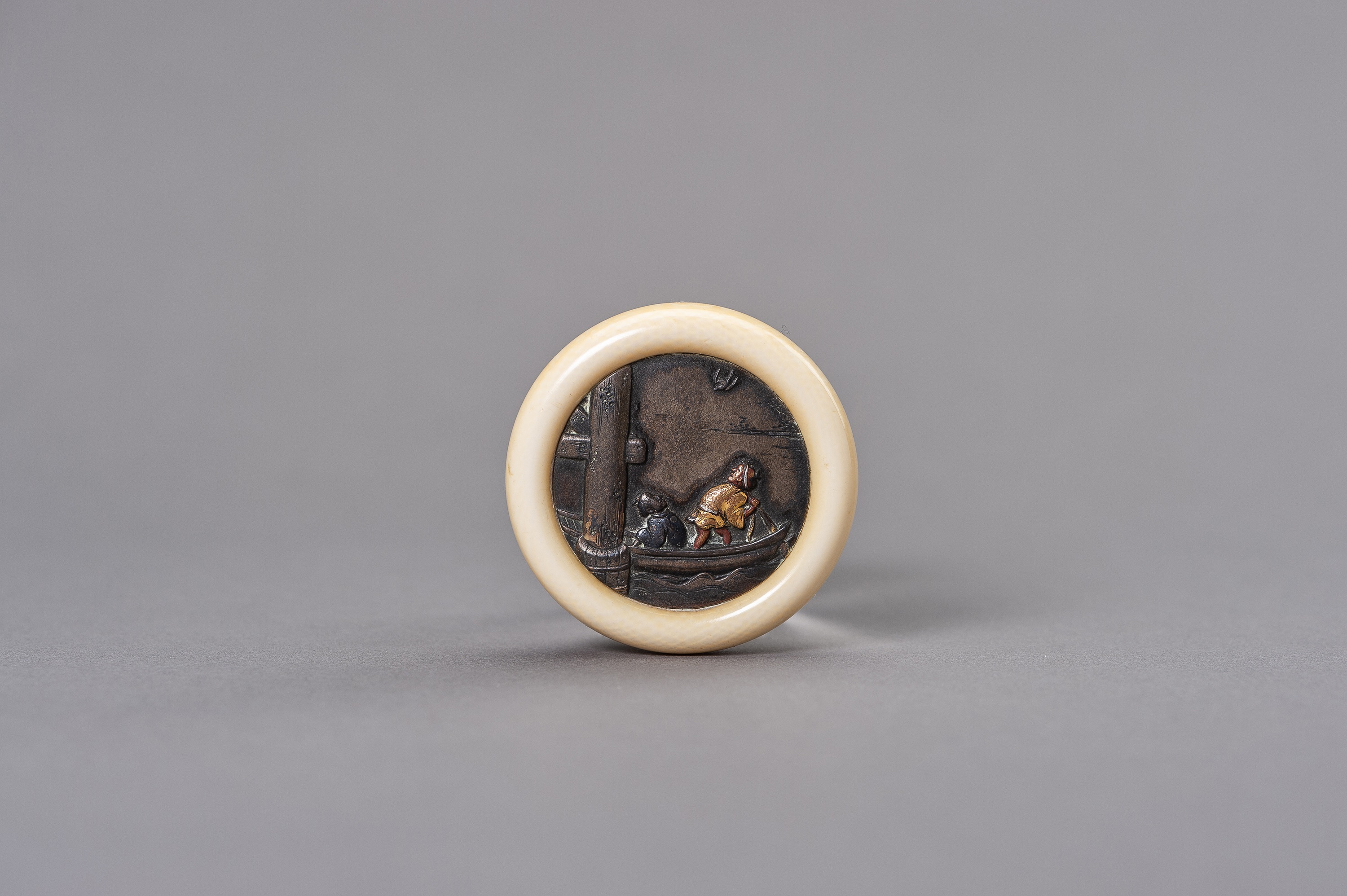 AN IVORY AND MIXED METAL KAGAMIBUTA NETSUKE DEPICTING TWO FIGURES ON A BOAT - Image 2 of 8